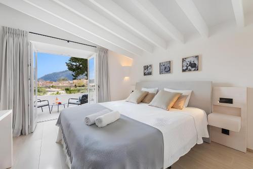 a white bedroom with a large bed and a balcony at Can Mas Villa Antigua in Pollença