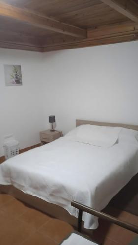 a white bed in a room with a wooden ceiling at Casa do Avô Almeida in Lajes das Flores