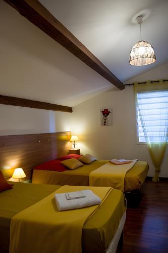 a bedroom with three beds with yellow sheets at Gite Le Calcadis in Mostuéjouls