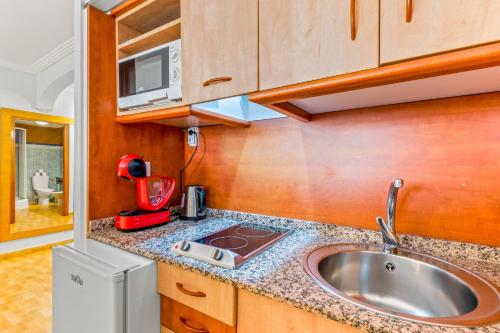 a kitchen with a sink and a microwave at Unique Apartahotel 3-3 in Torrevieja