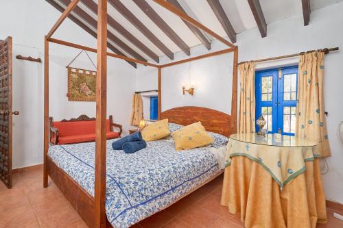 a bedroom with a canopy bed and a table at Villa Carlitos in Comares