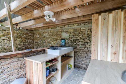 a kitchen with a sink and a stone wall at Tente Glamping Éco-Chic in Auriac-du-Périgord