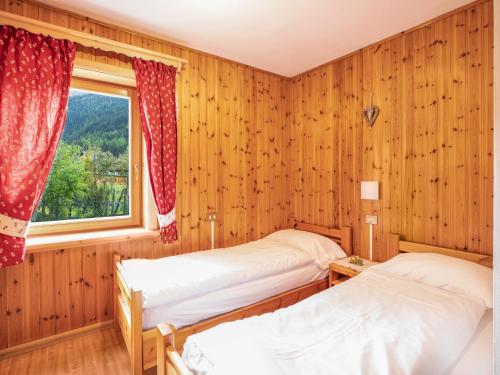 two beds in a wooden room with a window at Ciasa Lino Sas da le Undesc in Pozza di Fassa