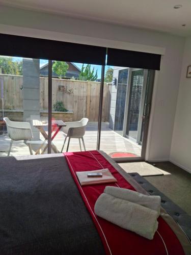 a bedroom with a bed and a large glass window at Studio Hugoway Papamoa Beach Winter Special in Papamoa