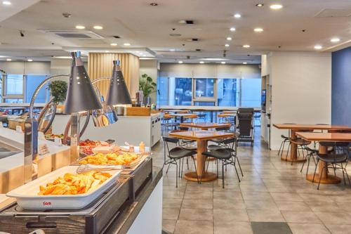 a restaurant with tables and chairs and food on display at Kolon Seacloud Hotel in Busan