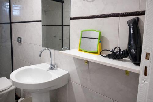 a bathroom with a sink and a mirror on a shelf at Casa Stepien ,Spacious House up to 11 guests in Fazenda Rio Grande Paraná Brazil in Fazenda Rio Grande