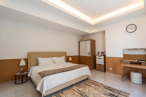 a bedroom with a large bed with a clock on the wall at Blue Marlin Villas Legian in Legian
