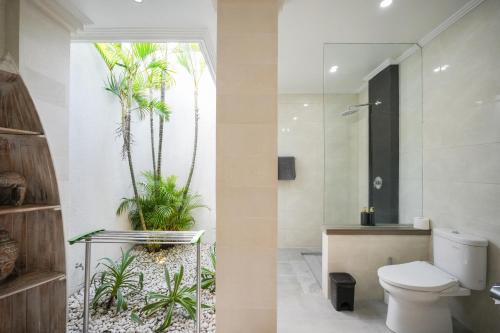 a bathroom with a toilet and palm trees in it at Blue Marlin Villas Legian in Legian