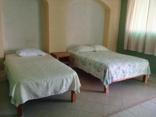 two beds sitting next to each other in a room at Hotel Mecalco in Huazuntlán