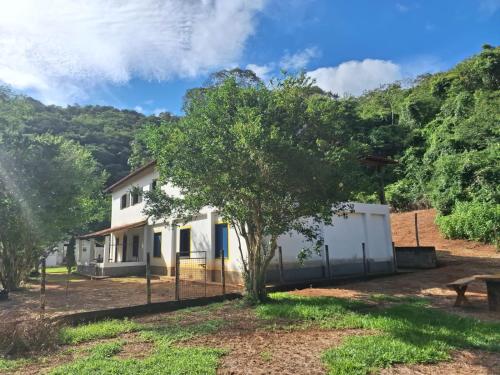 a house with a tree and a fence at Fazenda São Leandro in Rio das Flores