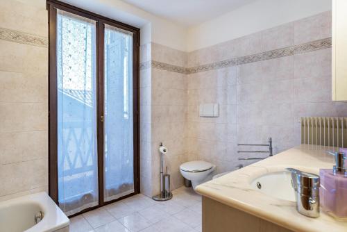 a bathroom with a toilet and a sink and a window at Appartamento Cles in Cles