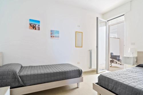 a bedroom with two beds and a sliding glass door at Casa d'a mare in Torre San Giovanni Ugento