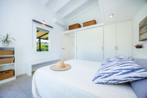 a white bedroom with a bed with a hat on it at Les Herbetes in Port de Pollensa