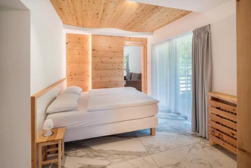 a bedroom with a bed and a wooden ceiling at Apart Wellness Alpino con minispa in Soraga