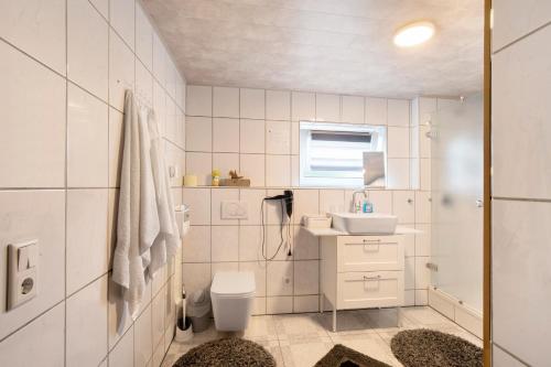 a white bathroom with a sink and a toilet at Ferienwohnung am Wartberg in Herbrechtingen