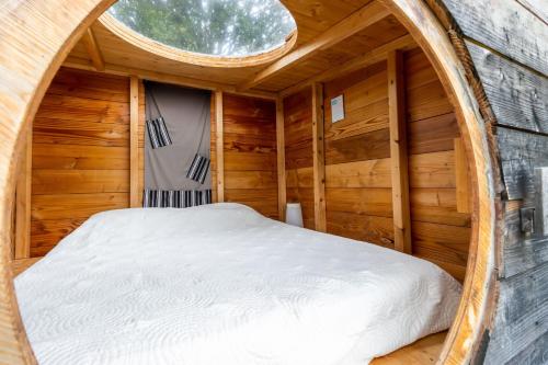 a bed in a wooden room with a round window at Cabane aux étoiles in Auriac-du-Périgord