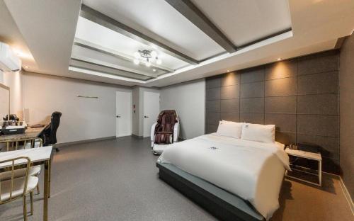 a bedroom with a bed and a desk and a kitchen at Iksan Hotel G7 in Songman