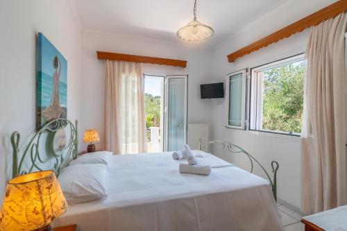 a bedroom with a white bed and a window at Captain Spiros Paxoi in Gaios
