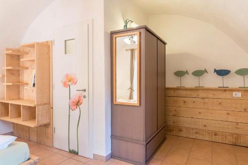 a room with a mirror and flowers on the wall at Moserhof Ferienwohnung Sunnseit in Sarntal