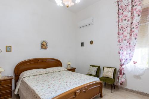a bedroom with a bed and two chairs at Sartiglia Domu in Oristano