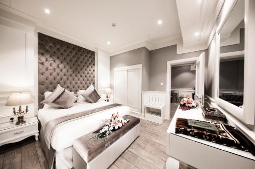 a white bedroom with a large bed and a fireplace at Aswar Boutique Hotel in Al Khobar