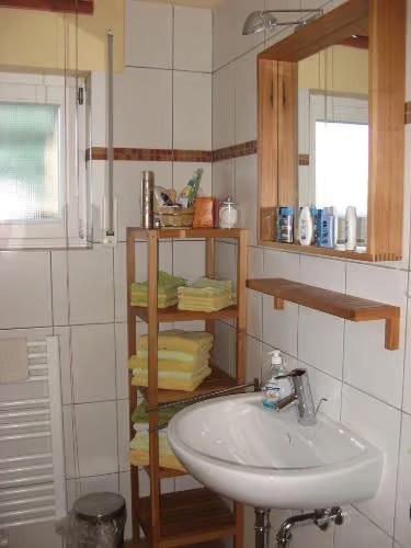 a bathroom with a sink and a shelf with towels at Ferienwohnung Wadle in Gleisweiler
