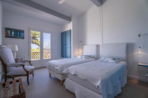 a bedroom with two beds and a chair and a window at Villa Baliba in Hyères