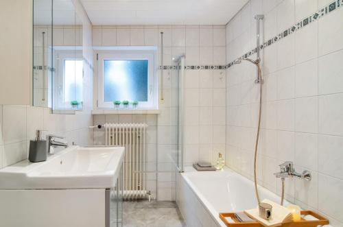 a white bathroom with a sink and a bath tub at Ferienwohnung Am Buchbühl in Stockach