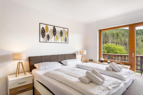 a bedroom with a large white bed with a window at Haus Sonnenblick in Diemelsee