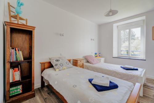 a bedroom with two beds and a book shelf at La ferme d'Alcide in Québriac
