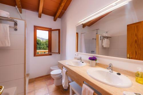 a bathroom with two sinks and a toilet and a mirror at Can Petit Estel in Betlem