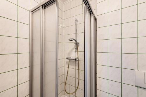 a shower in a bathroom with white tiled walls at Möve Aba Appartment 22 in Rerik