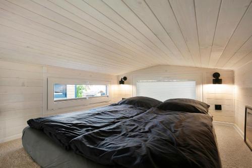 a large bed in a room with a wooden ceiling at Tiny House Nr 4 in Schwielowsee