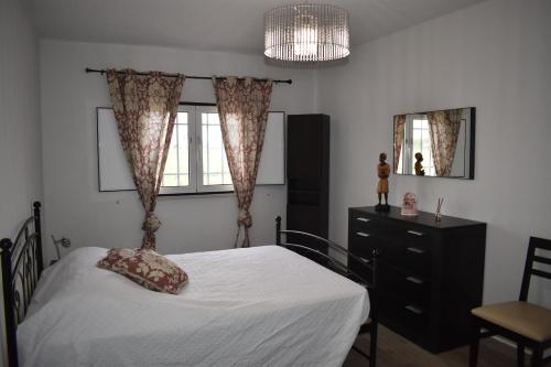 a bedroom with a bed and a dresser and a window at Casa Trincadeira in Palmela