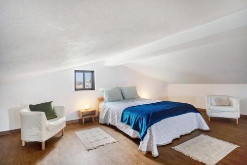 a white bedroom with a bed and two chairs at Bouros's Cliff in Serra do Bouro