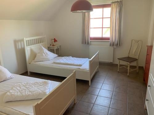 a bedroom with two beds and a window and a chair at Sabines Badehaus mit Innenpool in Steinkoppel