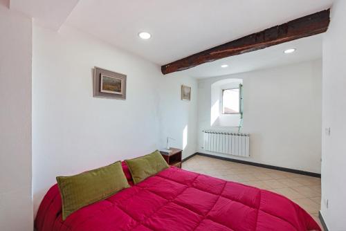 ein rotes Bett in einem weißen Zimmer mit einem Fenster in der Unterkunft Tavernetta in campagna in Zoagli