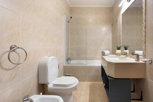 a bathroom with a toilet and a sink and a tub at Duo Village in Alvor