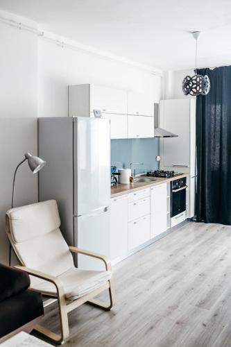 a white kitchen with a chair and a refrigerator at DD Apartments in Cluj-Napoca