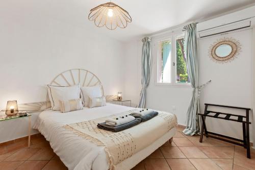 a bedroom with a large white bed with a chandelier at Villa à 200m de la plage in Sainte-Maxime