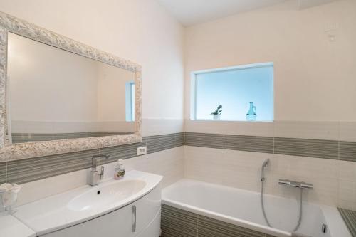 a bathroom with a tub and a sink and a mirror at Loggia Oliveto in Casanova Lerrore