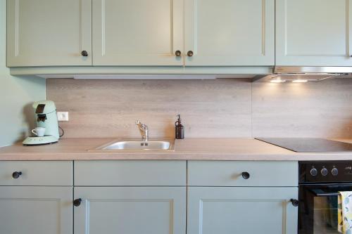 a kitchen with white cabinets and a sink at Ferienhaus Donauliebe in Vohburg an der Donau