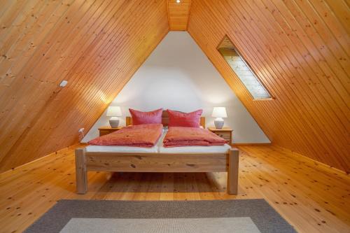 a bedroom with a bed with red pillows in a attic at Ferienhaus Kitzklause in Walkendorf