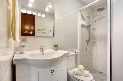 ein weißes Badezimmer mit Waschbecken und Dusche in der Unterkunft Simão House in Calheta