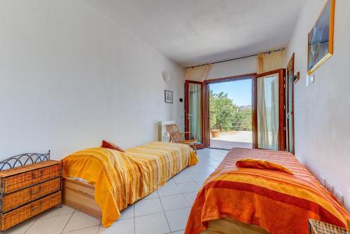 a bedroom with two beds and a large window at Appartamento Thomas in Capoliveri
