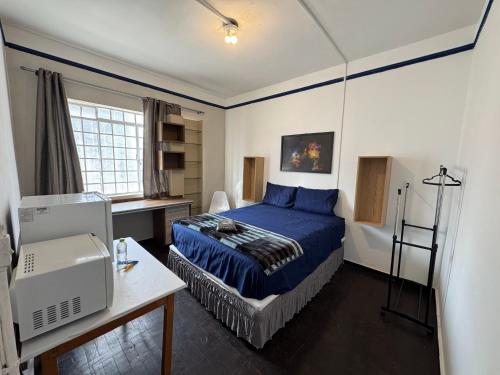 a bedroom with a blue bed and a desk at Pousada Solar de Mayo in Curitiba
