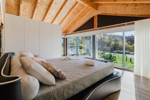 a bedroom with a large bed and a large window at Dunas e Abraços in Braga
