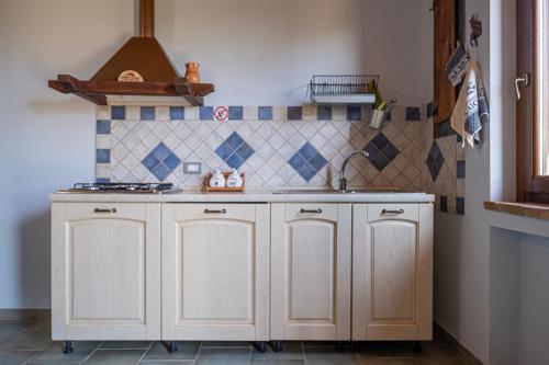 a kitchen with white cabinets and a sink at La Svolta - Aria in Manciano