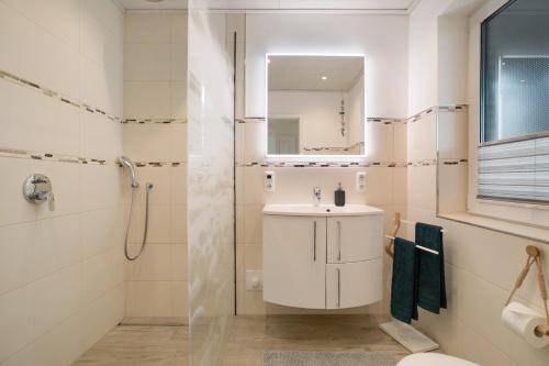 a white bathroom with a sink and a shower at Ferienhaus Martje in Hennstedt