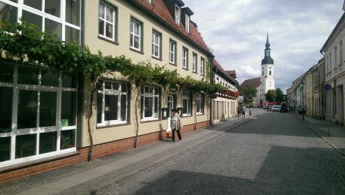 una mujer caminando por una calle al lado de los edificios en Lausitzhof, en Lübbenau